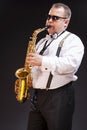 Portrait of Expressive Caucasian Saxophonist in White Shirt Posing in Sunglasses Against Seamless Black Background