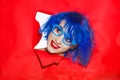 Portrait of an extravagant woman with blue hair and glasses looking through hole in paper wall Royalty Free Stock Photo