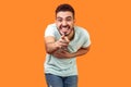 Portrait of extremely happy brunette man pointing at camera and laughing. indoor studio shot isolated on orange background