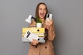 Portrait of extremely happy young pretty woman wearing beige jacket holding documents and her office stuff posing isolated over Royalty Free Stock Photo