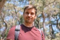 Portrait of face happy smiling unshaven mature 40+ years man solo traveler with stubble and a backpack on the background of green Royalty Free Stock Photo