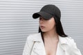 Portrait of the face of a pretty beautiful brunette young woman in a stylish black baseball cap in a fashionable Royalty Free Stock Photo