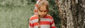 Portrait face of upset or focused thoughtful scowl eight year old kid girl in hood of striped hoodie in the forest or woodland nat