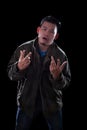 portrait face of young asian man acting like a rocker man standing against dark background