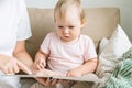 Portrait of faceless female pointing out in book to serious blond child sitting on sofa. Close up Royalty Free Stock Photo