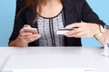 Portrait of faceless woman wears black suit using cell phone and credit card while sitting at white table near laptop computer and Royalty Free Stock Photo