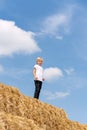 Portrait of fair-haired boy of seven years old on haystack against background of blue skies and clouds. Summer vacation Royalty Free Stock Photo