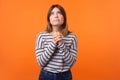 Portrait of faithful young woman with brown hair in long sleeve shirt. indoor studio shot isolated on orange background