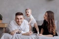 Portrait of a family on the bed at home while playing with their baby girl - Father, mother and one year old little daughter have Royalty Free Stock Photo