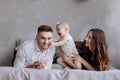 Portrait of a family on the bed at home while playing with their baby girl - Father, mother and one year old little daughter have Royalty Free Stock Photo