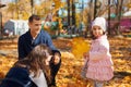 portrait of a family with children in an autumn city park, happy people walking together, playing with yellow leaves, beautiful Royalty Free Stock Photo