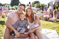 Portrait Of Family With Children Sitting On Rug At Summer Garden Fete