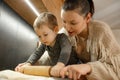 Portrait of family of cute little boy, young woman baking in kitchen at home. Baby toddler rolling dough with mother. Royalty Free Stock Photo