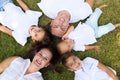 Portrait of a family of five, father, mother and children lying on the fresh grass looking at the camera. It is an example of a