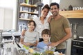 Portrait Of Family In Kitchen Following Recipe On Digital Tablet Royalty Free Stock Photo