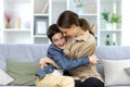 Portrait of a family, mother and teenage son sitting at home on the couch and hugging, having fun, laughing Royalty Free Stock Photo