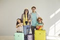 Portrait of a family with packed suitcases standing in the room on a background of a gray wall.