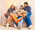 Portrait of a family sitting on a sofa at home, four people having fun together