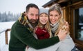 Portrait of family with small daughter outdoors in winter holiday cottage, looking at camera. Royalty Free Stock Photo