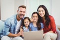 Portrait of family smiling and using laptop on sofa Royalty Free Stock Photo