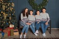 Portrait of a family with two children in a family look sitting on a sofa near a New Year`s decorated Christmas tree
