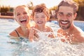 Portrait Of Family With Young Son Having Fun On Summer Vacation Splashing In Outdoor Swimming Pool Royalty Free Stock Photo