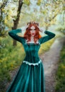 Portrait fantasy red-haired woman medieval queen touches with hands straightens golden crown on head. Girl redhead Royalty Free Stock Photo