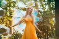 Portrait fantasy woman blonde forest fairy. Elf girl fashion model in bright yellow dress, butterfly wings. Pixie walks Royalty Free Stock Photo