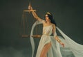 Portrait fantasy woman Greek goddess of justice Themis holding golden scales in hands. White silk vintage dress old Royalty Free Stock Photo