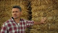 Portrait farmer inspect field in autumn. Focused farmland worker lean hay stack