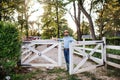 A portrait of farmer walking outdoors on family farm, opening gate. Royalty Free Stock Photo