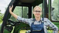 Portrait of a farmer woman. Standing near his tractor, looking at the camera