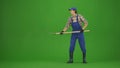 Portrait of farmer in working clothing on chroma key green screen. Gardener standing holding pitchfork for collecting