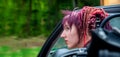 Portrait of a fascinating extraordinary extravagant punk woman with pink, violet, red, dreadlocks hair in a classic sports car Royalty Free Stock Photo