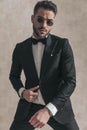 Portrait of fashion elegant guy adjusting black tuxedo and posing Royalty Free Stock Photo