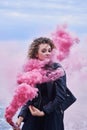 Portrait of fashion model girl in black clothes posing with a pink smoke bomb Royalty Free Stock Photo