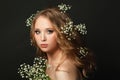 Portrait of fashion model girl with blonde curly hair and white flowers on head, beautiful face closeup Royalty Free Stock Photo