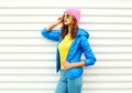 Portrait of fashion pretty woman model in colorful clothes posing over white background wearing a pink hat yellow sunglasses Royalty Free Stock Photo