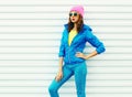 Portrait fashion pretty woman model in colorful clothes posing over white background wearing a pink hat yellow sunglasses Royalty Free Stock Photo