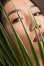 Portrait fashion young asian beautiful woman with extended eyelashes in tropical palm leaves background. Concept flora Royalty Free Stock Photo