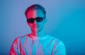 Portrait of fashion young man in white t-shirt and black sunglasses in red and blue neon light Royalty Free Stock Photo