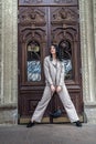 Portrait of fashionable beautiful young woman posing outside against old door of house Royalty Free Stock Photo