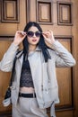 Portrait of fashionable beautiful young woman posing outside against old door of house Royalty Free Stock Photo