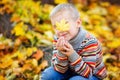 Portrait of a fashionable boy in the open air against a background of yellow leaves. Cute boy walking in the autumn Park. The