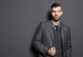 Portrait of fashionable confident handsome man in suit on gray wall background. Businessman looks seriously look