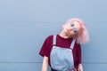 Portrait of a fashionable girl in stylish clothes, pink hair and sunglasses that lays on the background of a blue wall Royalty Free Stock Photo