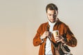 portrait of fashionable man with bag looking at disposable cup of coffee in hand Royalty Free Stock Photo