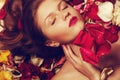 Fashionable red-haired ginger model with sexy pink lips lying on fading rose petals background. Close up. Copy- Royalty Free Stock Photo