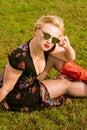 Portrait of fashionable woman holding shades sitting on grass Royalty Free Stock Photo