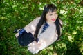 Portrait of an fat chubby plump girl with black hair and blossoming apple tree with white flower background in the park in a